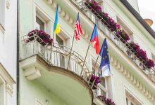 Building with flags on balconies and pink flowers