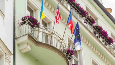 Building with flags on balconies and pink flowers