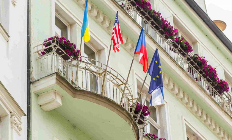 Building with flags on balconies and pink flowers