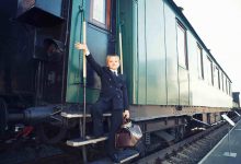 Young boy on train steps with brown bag