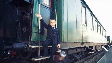 Young boy on train steps with brown bag