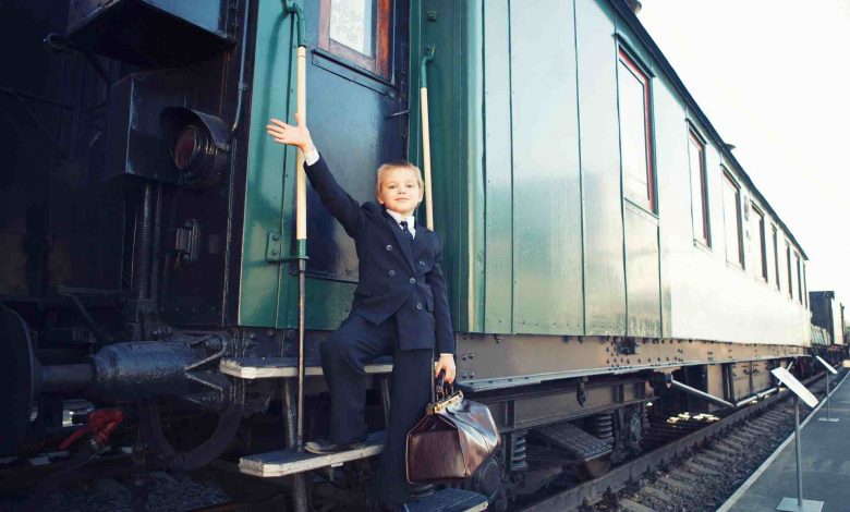 Young boy on train steps with brown bag