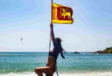 Carefree woman swinging on beach with flag