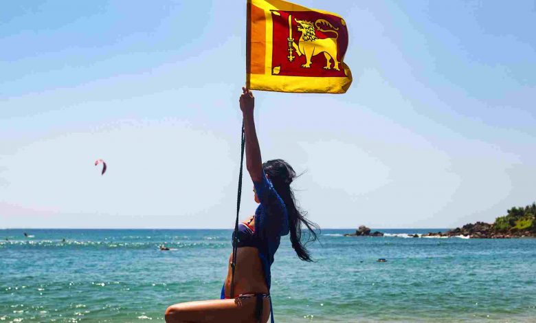 Carefree woman swinging on beach with flag