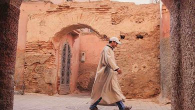 A man in a long coat walking down a street