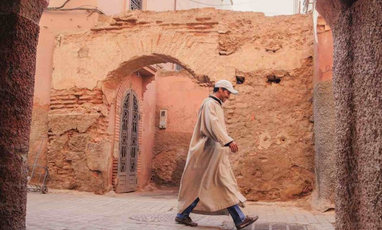 A man in a long coat walking down a street