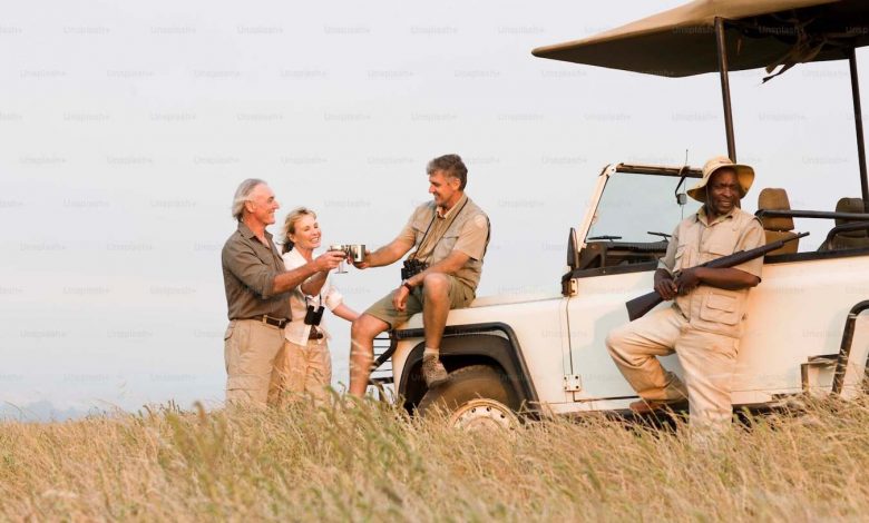 A group of people standing next to a safari vehicl